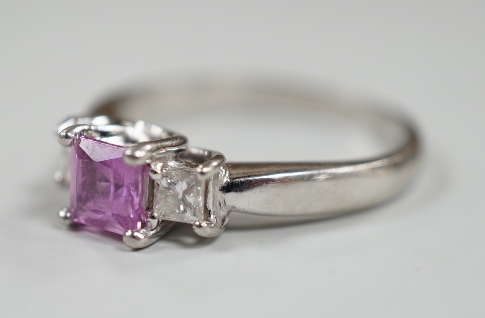 A modern platinum, single stone square cut pink sapphire and two stone diamond set ring, size N/O, gross weight 5.5 grams.